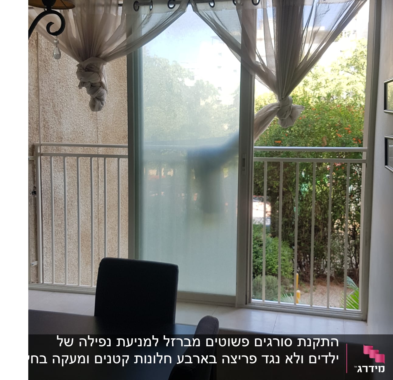 חלון עם וילונות קשורים ומעקה מתכת